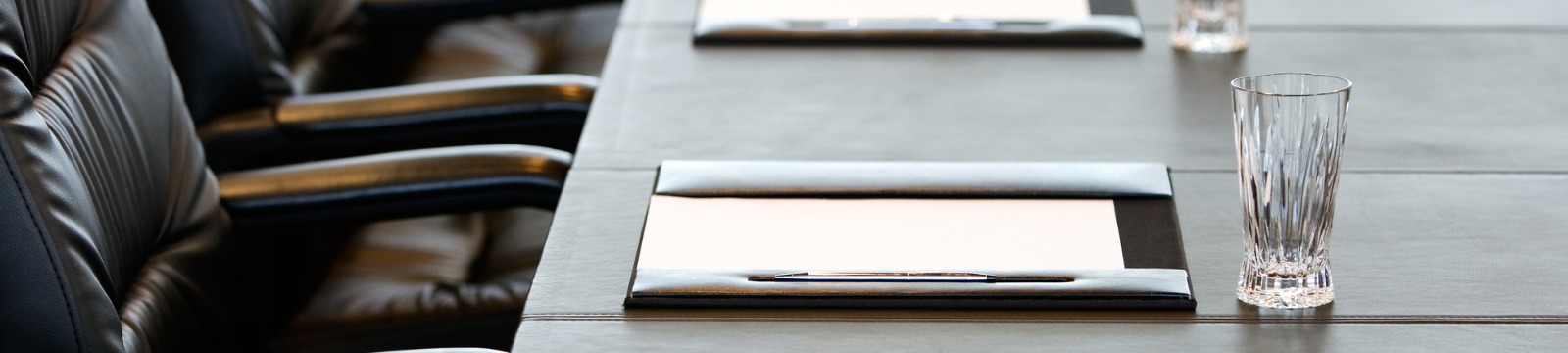 board room table with a drinking glass, pen, and a chair